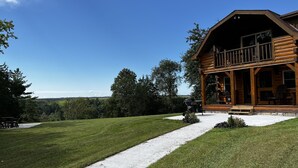 A log cabin with a balcony, surrounded by a well-maintained lawn and a gravel path leading to the entrance. - Heritage hideaway-Secluded Log Cabin (Chatfield)