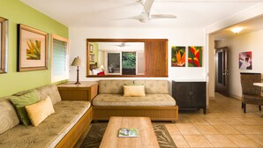 A living room with a sofa, a coffee table, a side table with a lamp, a cabinet, and a dining area with a chair.