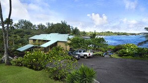 A hotel with a parking area, a building with a green roof, and a view of the ocean.