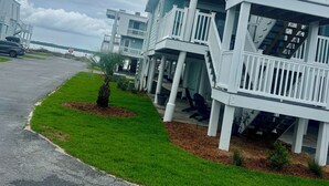 Propiedad frente a la playa con edificios de varios pisos, balcones y un césped.