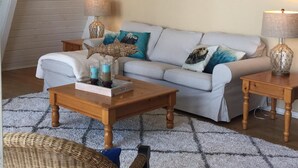 A cozy loft-style living room with a high ceiling, a large round wall clock, a sofa with cushions, a coffee table, and a wicker chair. - Waterfront & View-Near Seattle on Lake Sammamish in Bellevue (Bellevue)