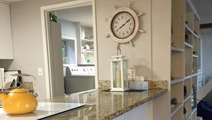 A kitchen with a granite countertop, white cabinets, a yellow kettle, a clock, and a white chair. - Waterfront & View-Near Seattle on Lake Sammamish in Bellevue (Bellevue)