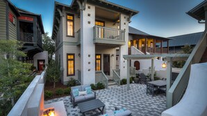 A two-story house with a balcony, outdoor seating area, and a fire feature. - Perfect Family Getaway | Bikes, Courtyard w/Fire Feature, Walk to Pool & Fitness (Rosemary Beach)