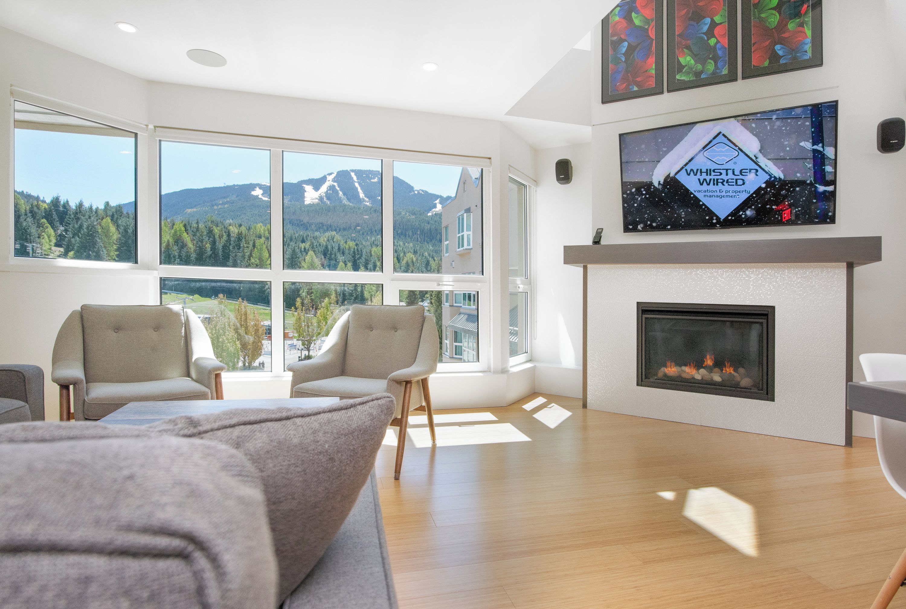 Una sala moderna con chimenea, ventanas amplias que ofrecen vistas a las montañas y un televisor montado.