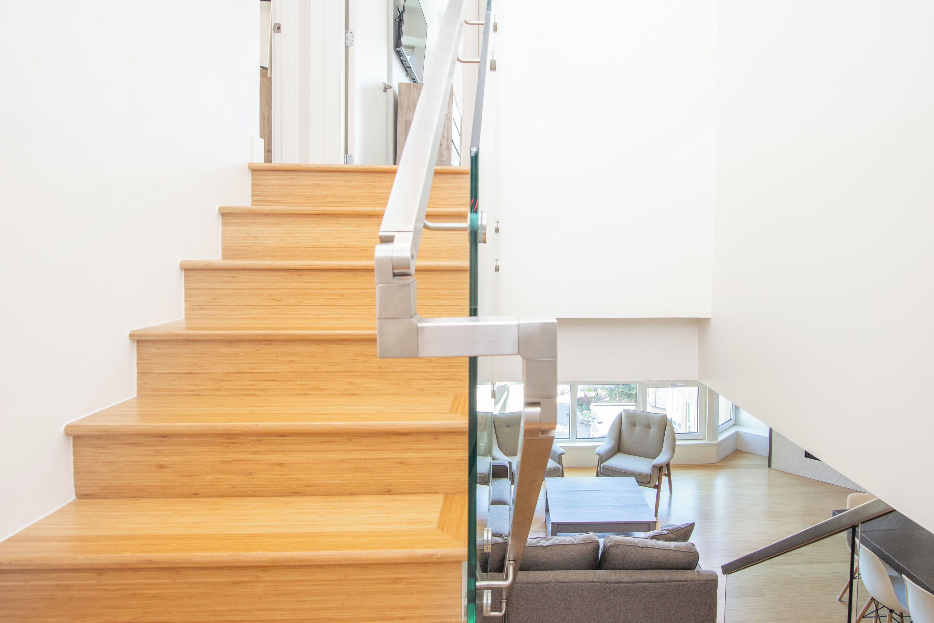 A wooden staircase leading to a modern living area with a sofa and a table.