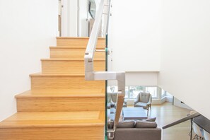 A wooden staircase leading to a modern living area with a sofa and a table. - Le Chamois 510 - Upper Village (Whistler)