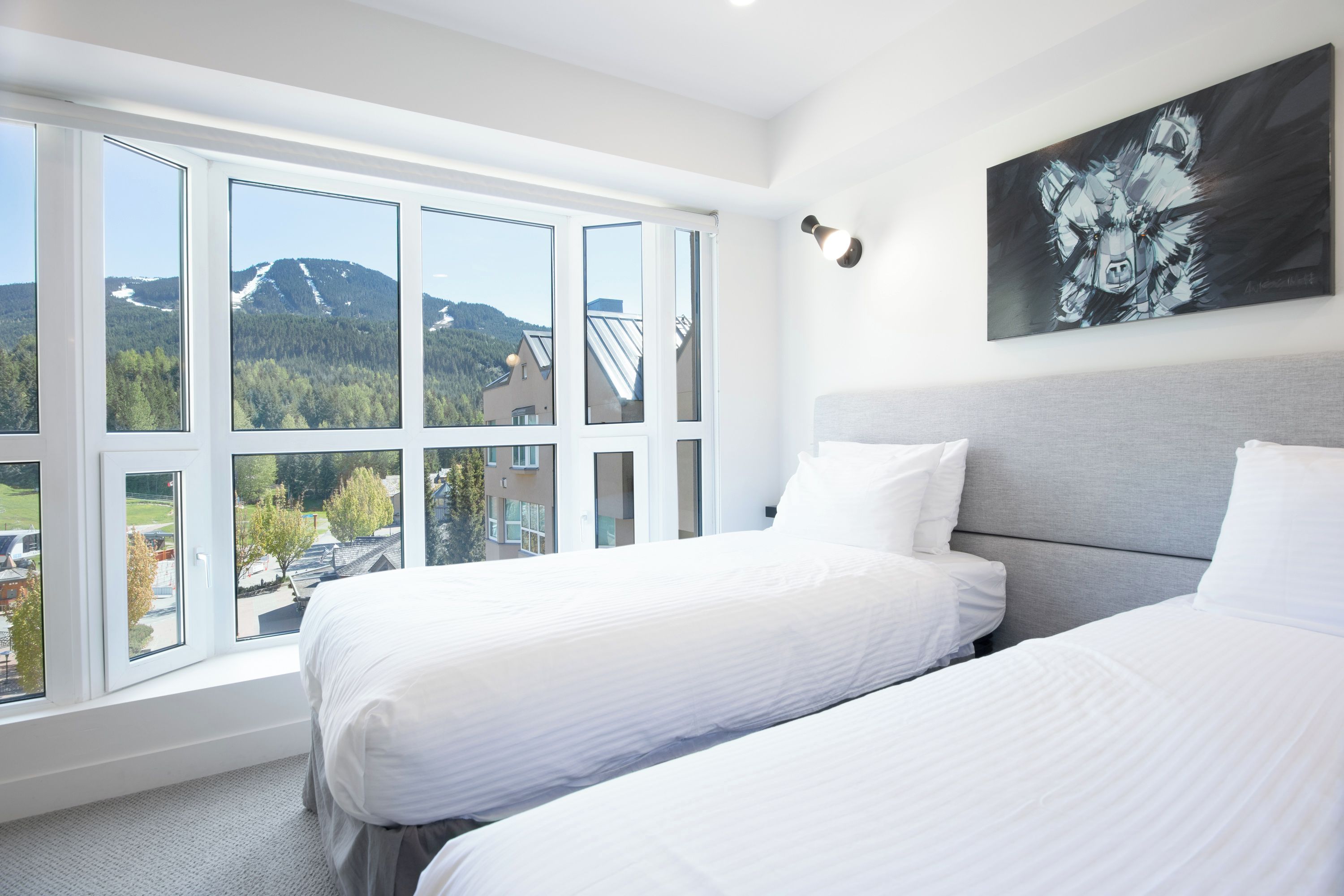 Habitación de hotel con dos camas, ventanas amplias y vista a la montaña.