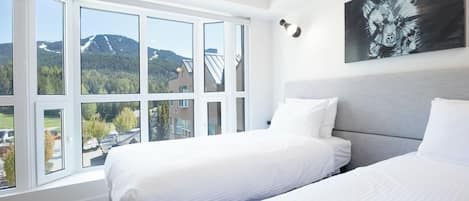 Habitación de hotel con dos camas, ventanas amplias y vista a la montaña.