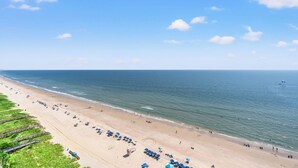 A beach with rows of umbrellas and sun loungers, a lifeguard tower, and a clear view of the ocean. - Nautical Oceanfront Condo, Jacuzzi Tub, Indoor Pool | Crescent Shores - S 1711 (North Myrtle Beach)
