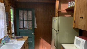 Ett kompakt kök med träskåp, ett kylskåp, en mikrovågsugn och en spis.