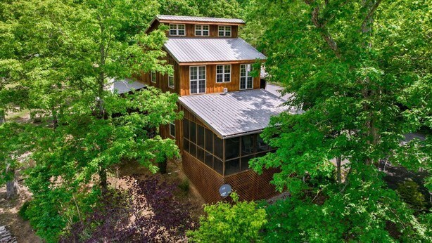 Eine zweistöckige Holzhütte, umgeben von dichtem Wald.