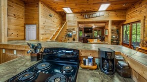 Ein Holzhütten-Interieur mit Küchenbereich, inklusive Herd, Kaffeemaschine und Esstisch.