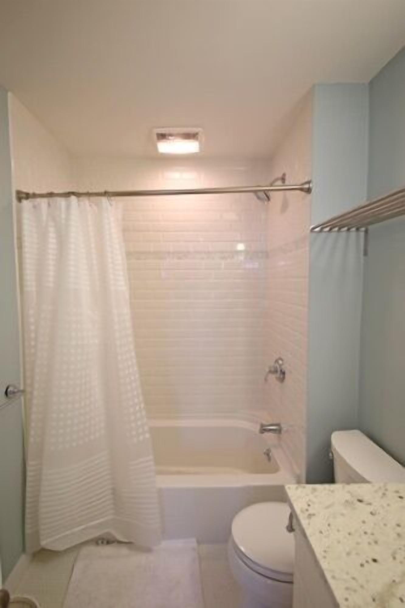 A bathroom with a bathtub, toilet, and a shower curtain.
