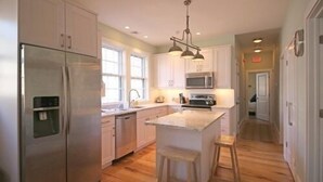 A modern kitchen with stainless steel appliances, a central island, and wooden flooring.