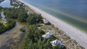 Une propriété située sur la côte, avec un étroit canal, un accès à la plage et plusieurs bâtiments.