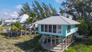 Une maison de plage avec une terrasse et un porche abrité.
