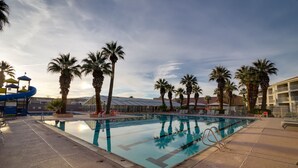 A swimming pool with palm trees, a slide, and a building with a balcony in the background. - Las Palmas! Beds for 9-10! 3Bed 2Bath, Bunks for kids! Huge deck! (St George)
