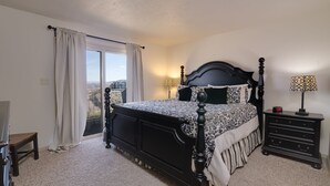 A bedroom with a large bed, a nightstand, a lamp, and a view of the outside. - Las Palmas! Beds for 9-10! 3Bed 2Bath, Bunks for kids! Huge deck! (St George)