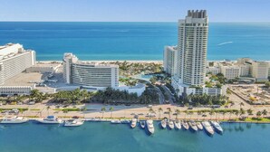 Un hotel moderno con vista a un puerto deportivo y una playa al fondo.