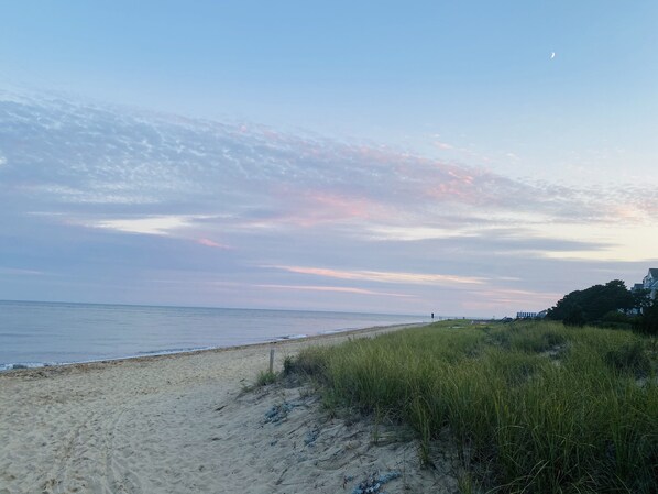 A beach with a clear sky and a crescent moon.