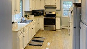 Une cuisine moderne avec des armoires blanches, des appareils en acier inoxydable et un plancher en bois.