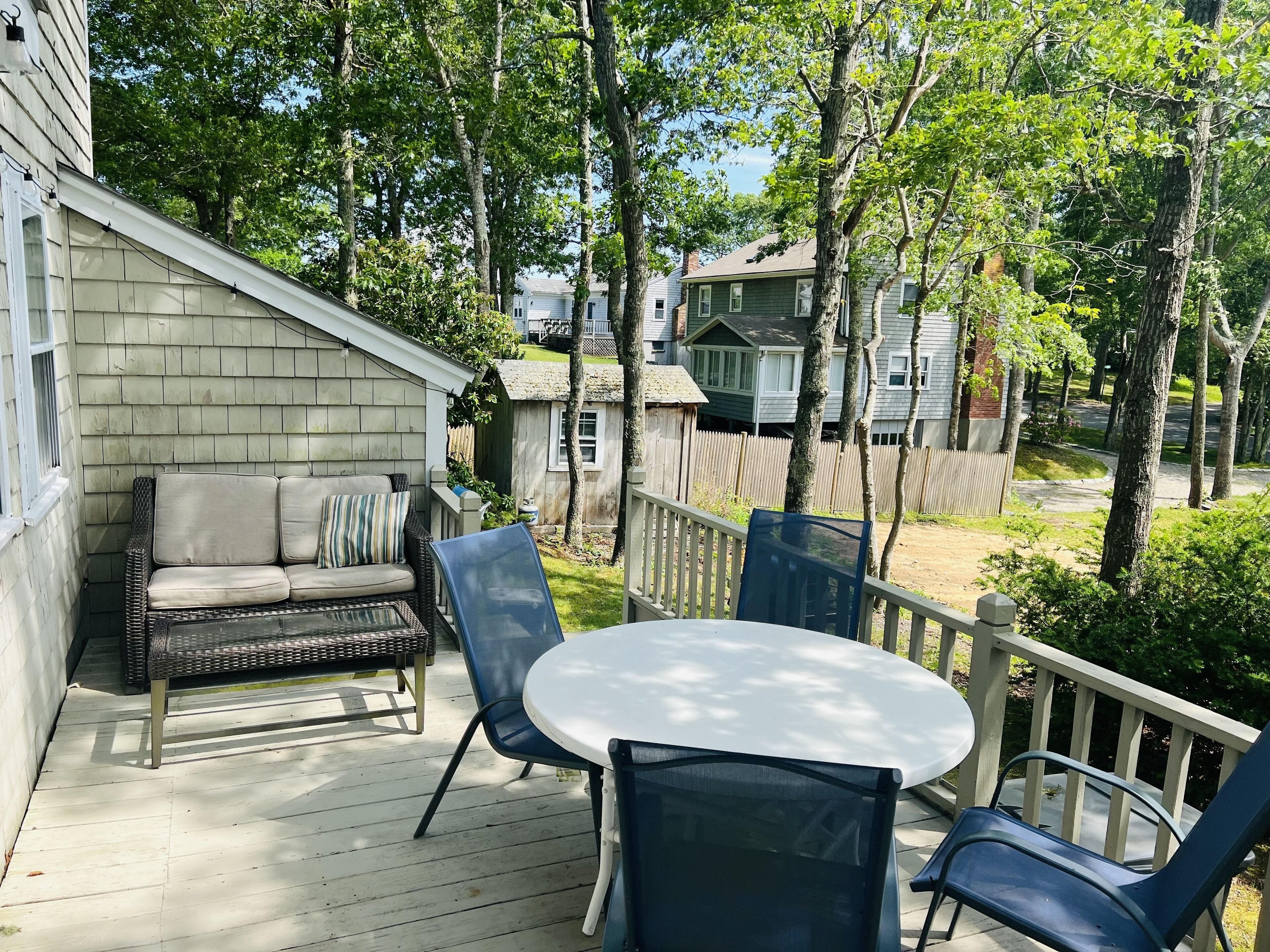 A covered outdoor patio with a wicker sofa and a round table with chairs.