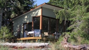 En moderne hytte med store vinduer, en balkon og en skovagtig beliggenhed.
