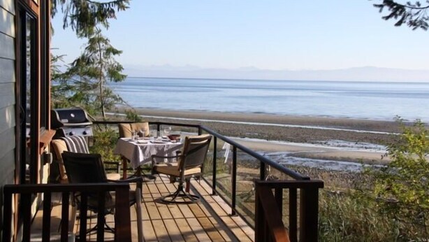 En terrasse med et bord og stole med udsigt over stranden.