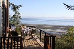 Une terrasse avec une table et des chaises donnant sur une plage.