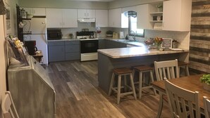 Una cucina moderna con mobili grigi, una stufa nera e un tavolo da pranzo in legno con sgabelli da bar.