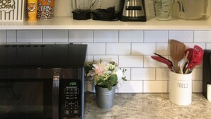 Una cucina con contenitori portaoggetti, un forno a microonde e una macchina per il caffè.