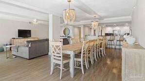 A spacious living area with a dining table, sofas, and a kitchen in the background. - Multi-Family, sleeps 12, GULF FRONT with BEACH VIEWS FROM EVERY ROOM (Pensacola Beach)