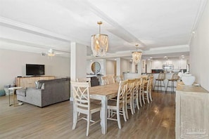 A spacious living area with a dining table, sofas, and a kitchen in the background. - 4bd Luxury home, sleeps 12, 2 refrigerators, In unit laundry, Gulf/ Beach front (Pensacola Beach)