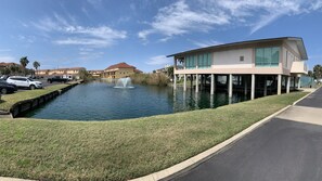 A waterfront property with a swimming pool, a fountain, and a modern building with a flat roof and large windows. - Multi-Family, sleeps 12, GULF FRONT with BEACH VIEWS FROM EVERY ROOM (Pensacola Beach)