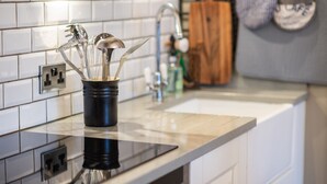 Una cucina con piano di lavoro nero, schienale piastrellato bianco e porta utensili in acciaio inossidabile.