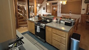 A modern kitchen with a central island, built-in oven, and wooden cabinets. A staircase leads to an upper level. - Pine Lodge - 9 beds;  Extra fees  for 7+ Hot Tub Sauna AC EV Charger Pets (Packwood)