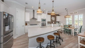 Een moderne keuken met witte kasten, roestvrijstalen apparatuur en een centraal kookeiland met krukken.