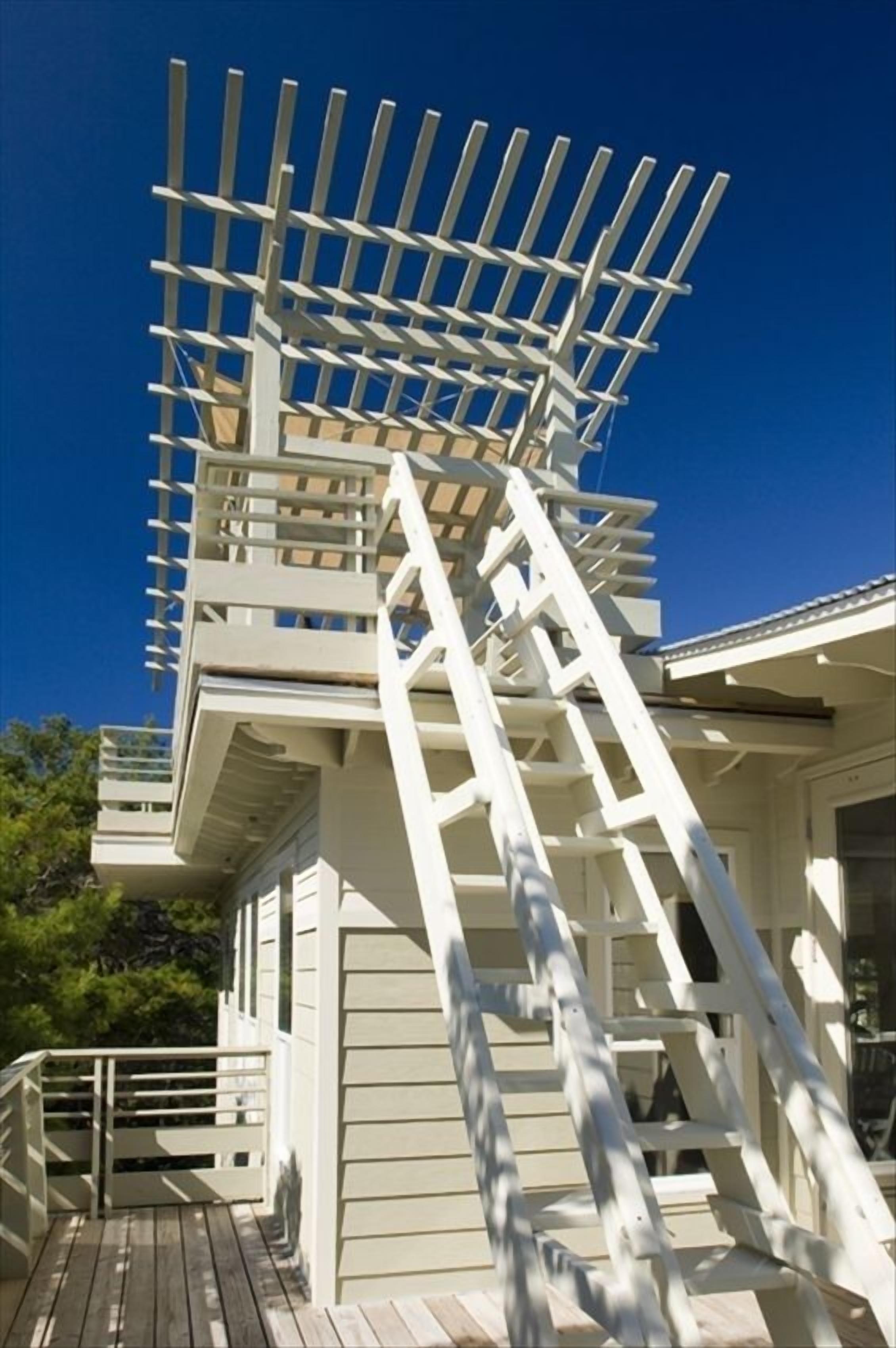 Una terraza de madera blanca con una serie de escalones que llevan a un balcón blanco.