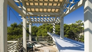 A wooden deck with a pergola, a hammock, and a bench.
