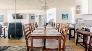 A dining area with a long table, chairs, and a chandelier.