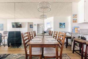 A dining area with a long table, chairs, and a chandelier. - Gorgeous Ocean Front  Condo on the Boardwalk - Walk to Everything! (San Diego)