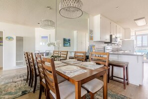 A modern kitchen with white cabinets, a central island, and a dining area with wooden chairs and a table set for four.