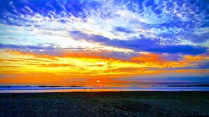 A beach at sunset with a clear sky and ocean waves.