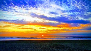 A beach at sunset with a clear sky and ocean waves.