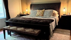 A bedroom with a large bed, a bench, a nightstand, and a lamp. - Private 5 Acres in Packwood, close to Cowlitz River, Mt. Rainer & White Pass. (Packwood)