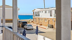 A coastal building with a view of the sea, a parking area with cars, and a no parking sign.