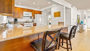 A modern kitchen with wooden cabinets, a granite countertop, and a stainless steel range hood.