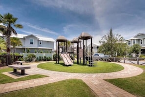 Ein Spielplatz mit Rutschen und einem Picknicktisch in einer Wohngegend.