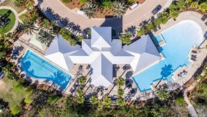 Vista aèria d'un complex turístic amb una piscina central en forma d'estrella, rodejada de palmeres i zones de relaxació.