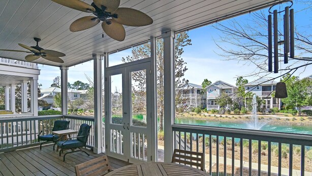 A covered porch with a table and chairs, a ceiling fan, and a view of a river and houses in the background. - 6-Seater Golf Cart & 6 Bikes! Newly Furnished! 2 Resort Pools! Sunset at Seagrove on 30A (Santa Rosa Beach)